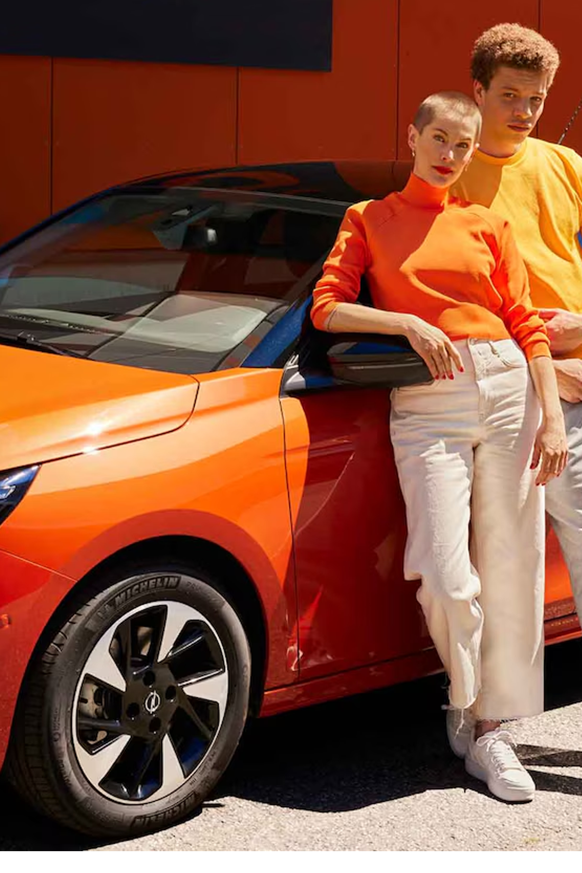 Ausschnitt eines orangener Opel mit zwei Personen, die sich anlehnen